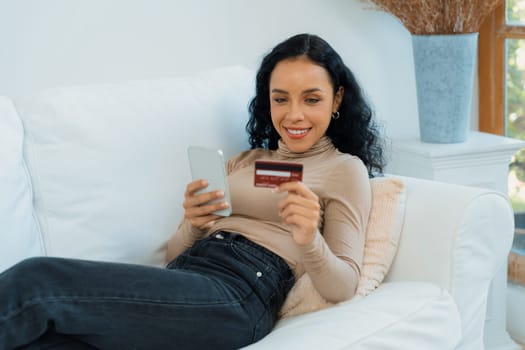 Young happy woman buy product by online shopping at home while ordering items from the internet with credit card online payment system protected by crucial cyber security from online store platform