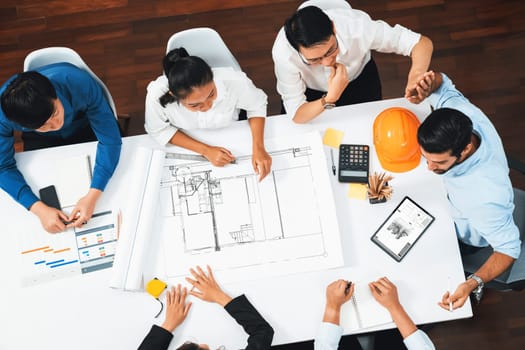 Top view banner of diverse group of civil engineer and client working together on architectural project, reviewing construction plan and building blueprint at meeting table. Prudent