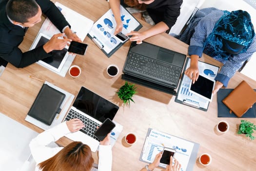 Top view of businessman executive in group meeting with other businessmen and businesswomen in modern office with laptop computer, coffee and document on table. People corporate business team uds