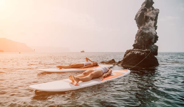 Woman sup yoga. Middle age sporty woman practising yoga pilates on paddle sup surfboard. Female stretching doing workout on sea water. Modern individual hipster outdoor summer sport activity