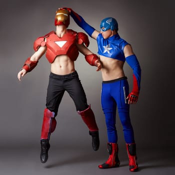 Men posing in costumes of Iron man and Captain America, on grey backdrop
