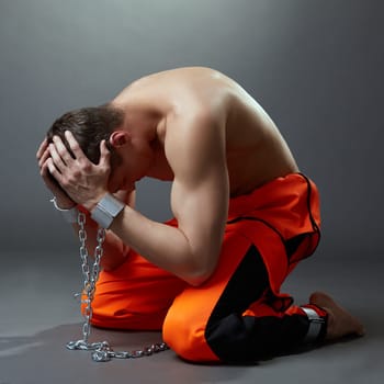 Concept of imprisonment. Prisoner grabbed his head, on grey background