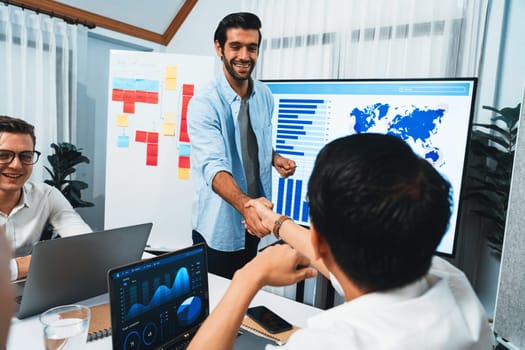 Analyst team leader shake hand with his colleague after successful data analysis meeting using FIntech software power with business intelligence or BI dashboard. Prudent