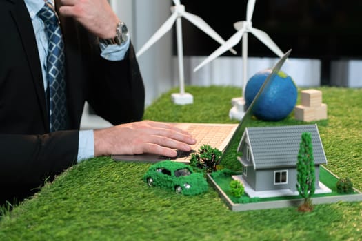 Businessman planning on his laptop for implementation of clean and sustainable energy to reduce CO2 emission in eco green company with for greener sustainable Earth. Quaint