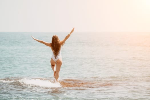 Woman sea yoga. Back view of free calm happy satisfied woman with long hair standing on top rock with yoga position against of sky by the sea. Healthy lifestyle outdoors in nature, fitness concept.