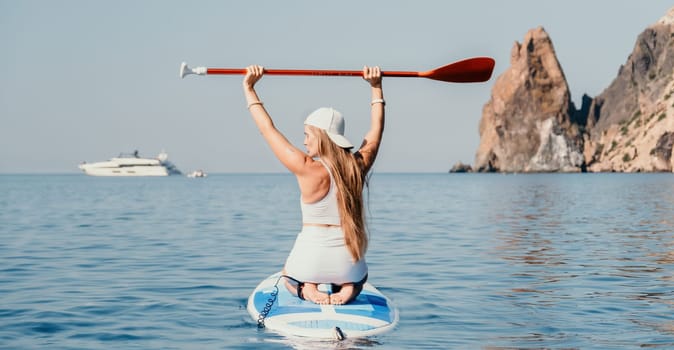 Close up shot of beautiful young caucasian woman with black hair and freckles looking at camera and smiling. Cute woman portrait in a pink bikini posing on a volcanic rock high above the sea