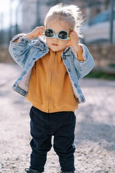 Little girl trying on sunglasses upside down. High quality photo