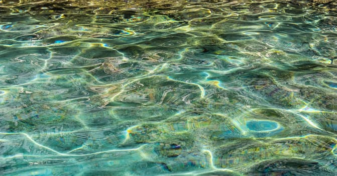 Emerald sea water in sunshine glow as surface background. Summer holidays concept