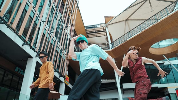 Caucasian group practice break dancing together. Energetic street dancer team in stylish fashion outfit perform hip-hop footstep at mall or city. Low angle view. Outdoor sport 2024. Endeavor.