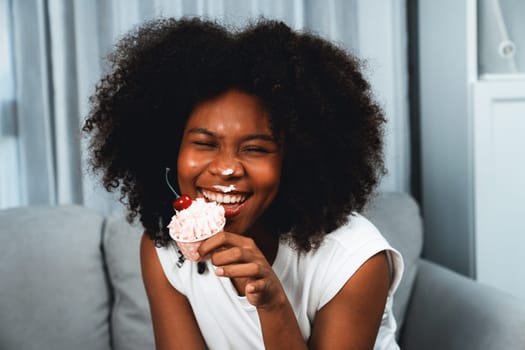 Funny beautiful young African blogger on mess face presenting cupcake in concept special cuisine. Content creating of social media online with favorite tasty sweets bakery dish. Tastemaker.