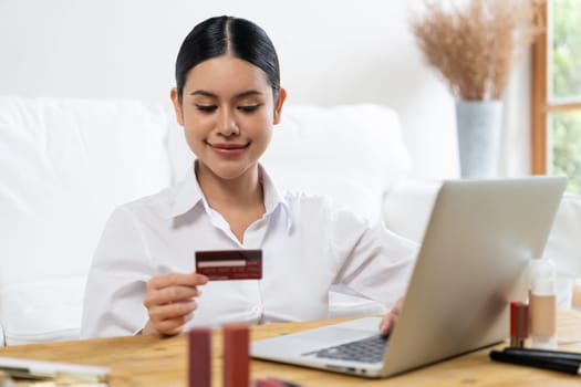 Young happy Asian woman buy product by online shopping at home while ordering items from the internet with credit card online payment protected by uttermost cyber security from online store platform