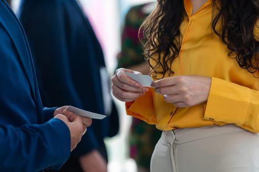 Successful businesswoman holding the name card during talking to manager about their cooperation. Cropped image of exchanging name card between businessman and businesswoman. Side view. Intellectual.