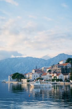 Tourist boat is moored to the coast of Perast against the backdrop of mountains. Montenegro. High quality photo