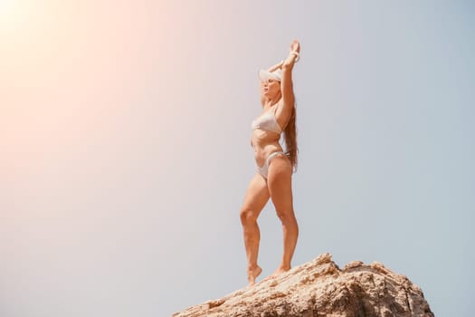 Woman meditating in yoga pose silhouette at the ocean, beach and rock mountains. Motivation and inspirational fit and exercising. Healthy lifestyle outdoors in nature, fitness concept.