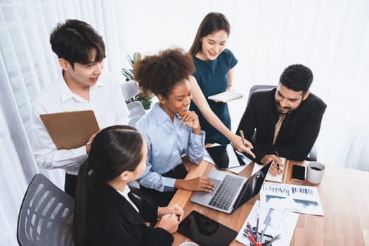 Multiracial analyst team use BI dashboard data to analyze financial report on meeting table. Group of diverse business people utilize data analysis by FIntech for success business marketing. Concord