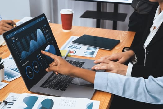 Multiracial analyst team use BI Fintech software to analyze financial data on meeting table. Financial dashboard data display on laptop screen with analyzed chart for marketing indication. Concord