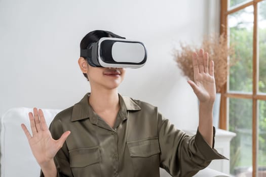 Young woman using virtual reality VR goggle at home for uttermost online shopping experience. The virtual reality VR innovation optimized for digital entertainment lifestyle.