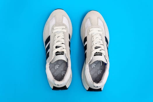 Tyumen, Russia-October 03, 2023: White adidas sneakers on blue background. New clean sneakers