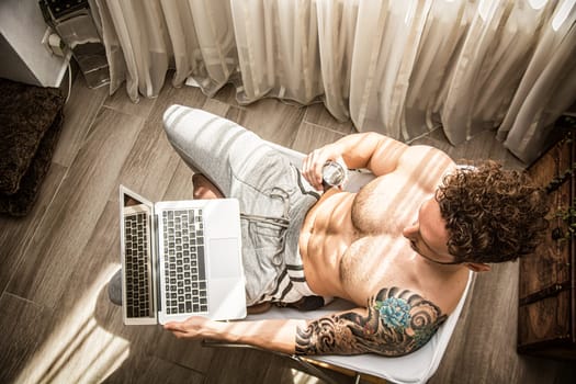 View from Above of Attractive Man with Muscular Body, Sitting with Computer Working on His Start-up Business