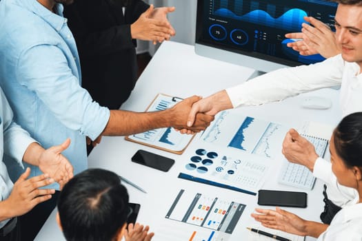 Diverse group of office employee worker shake hand after making agreement on strategic business marketing meeting. Teamwork and positive attitude create productive and supportive workplace. Prudent