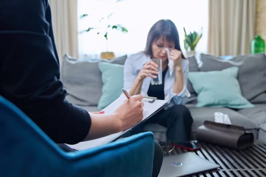 Sad upset crying middle-aged woman sitting on couch in therapy with psychologist counselor therapist. Psychology, psychotherapy, mental health, professional support, treatment, mature people concept