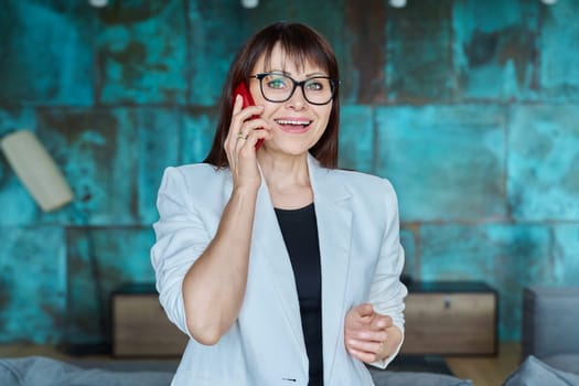 Confident successful mature business woman talking on mobile phone in office. Business call, conversation, work, management, financing, legislation concept