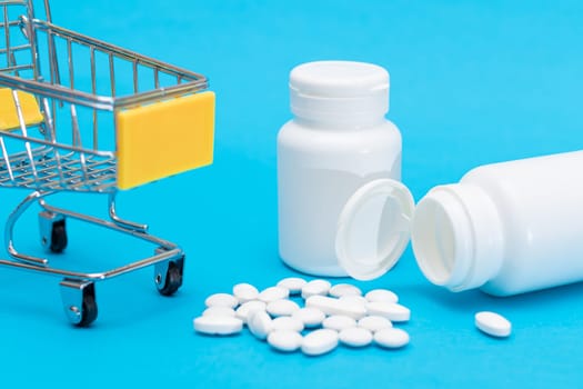 Buying Medicines. Expensive Medicine and Inflation: Scattered Pills or Capsules and Shopping Cart on Blue Background. Global Pharmaceutical Industry and Big Pharma. Ordering Pharmaceutical Products