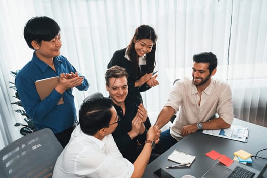 Diverse group of office employee worker shake hand after making agreement on strategic business marketing meeting. Teamwork and positive attitude create productive and supportive workplace. Prudent