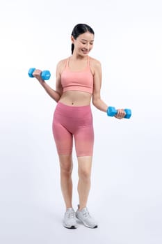 Vigorous energetic woman doing dumbbell weight lifting exercise on isolated background. Young athletic asian woman strength and endurance training session as body workout routine.