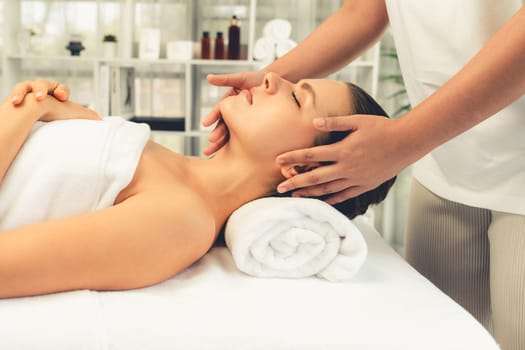 Caucasian woman enjoying relaxing anti-stress head massage and pampering facial beauty skin recreation leisure in dayspa modern light ambient at luxury resort or hotel spa salon. Quiescent