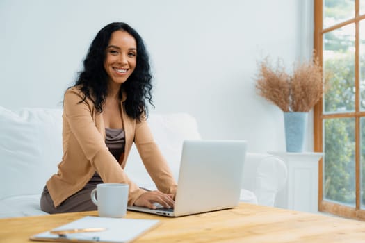 African-American woman using laptop computer for crucial work on internet. Secretary or online content writing working at home.