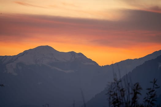 Sunrise sunset dusk dawn colors over the himalaya mountains with fog haze in distance with rich orange and red colors in manali kullu shimla in India