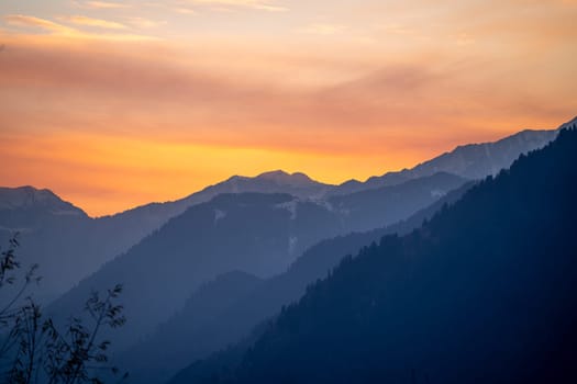 Sunrise sunset dusk dawn colors over the himalaya mountains with fog haze in distance with rich orange and red colors in manali kullu shimla in India