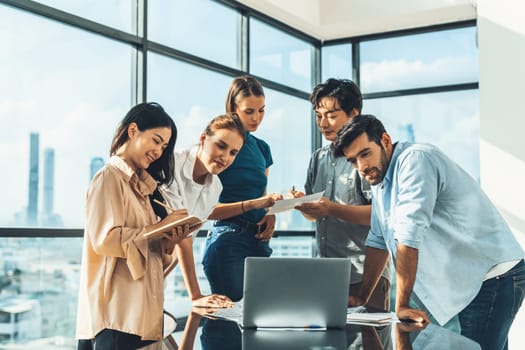 Asian project manager uses laptop displayed data analysis while professional business team brainstorming marketing idea at business meeting. Working together,sharing idea, planing strategy. Tracery.