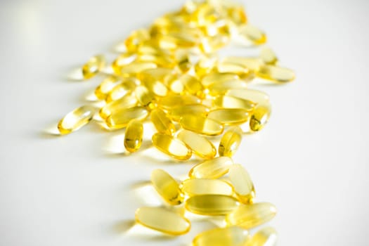 Pile of capsules Omega 3 on white table background. Close up, top view, high resolution product. Medical pill or vitamin's capsule pattern