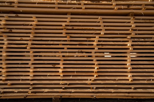 Stacked wooden boards at a outdoor lumber warehouse in a woodworking industry. Stacks with pine lumber. Folded edged board. Wood harvesting shop