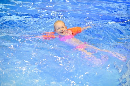 Cute girl with inflatables swimming in the pool. Healthy sport for children.