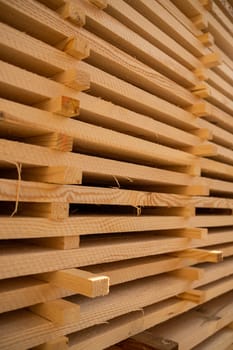 Stacked wooden planks in close-up at a outdoor lumber warehouse. Piles of wooden boards in the sawmill, planking. Warehouse for sawing boards on a sawmill outdoors. Wood industry
