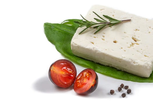 Feta cheese cubes isolated on white background with clipping path. Heap of Feta cheese, basil leaves and tomatoes.