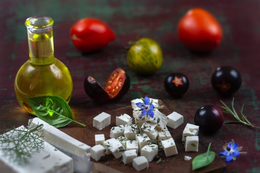 Bottle of olive oil and tomatoes with leaves feta and basil isolated on a brown background
