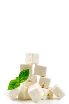 cheese cubes isolated on white background with clipping path. Heap of Feta cheese, basil leaves and tomatoes.