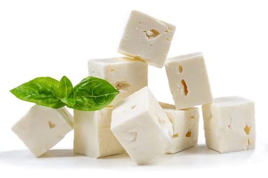 cheese cubes isolated on white background with clipping path. Heap of Feta cheese, basil leaves and tomatoes.
