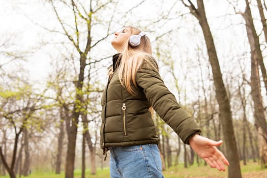 Relaxed woman wearing headphones breathing fresh air listening to music in a forest or park