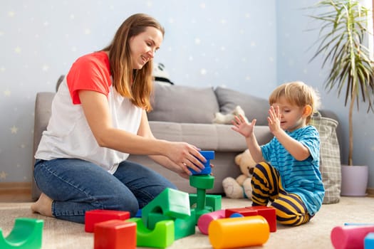 Happy loving family plays with plastic blocks and have fun. Mother and her baby son play together.