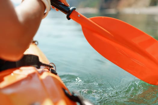 Kayak paddle sea vacation. Person paddles with orange paddle oar on kayak in sea. Leisure active lifestyle recreation activity rest tourism travel.