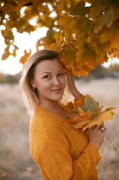 Woman holding autumn leafs in the nature. Autumn woman on leafs background.