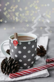 A large grey Cup of hot coffee drink with a Lollipop on a dark concrete background. Winter. Holiday concept, selective focus. Christmas coffee.