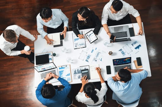 Top view analyst team utilizing BI Fintech to analyze financial data at table in meeting room. Analytic BI dashboard power on paper for business insight and strategic marketing planning. Prudent