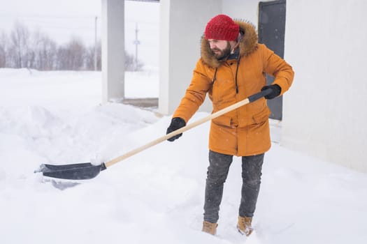 Man cleaning snow from sidewalk and using snow shovel. Winter season.