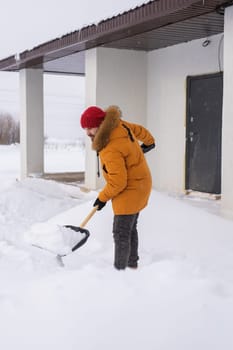 Man cleaning snow from sidewalk and using snow shovel. Winter season.